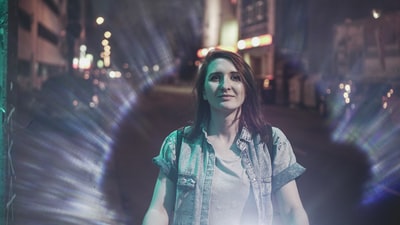 Dressed in a blue denim shirt buttons women standing in the road at night
